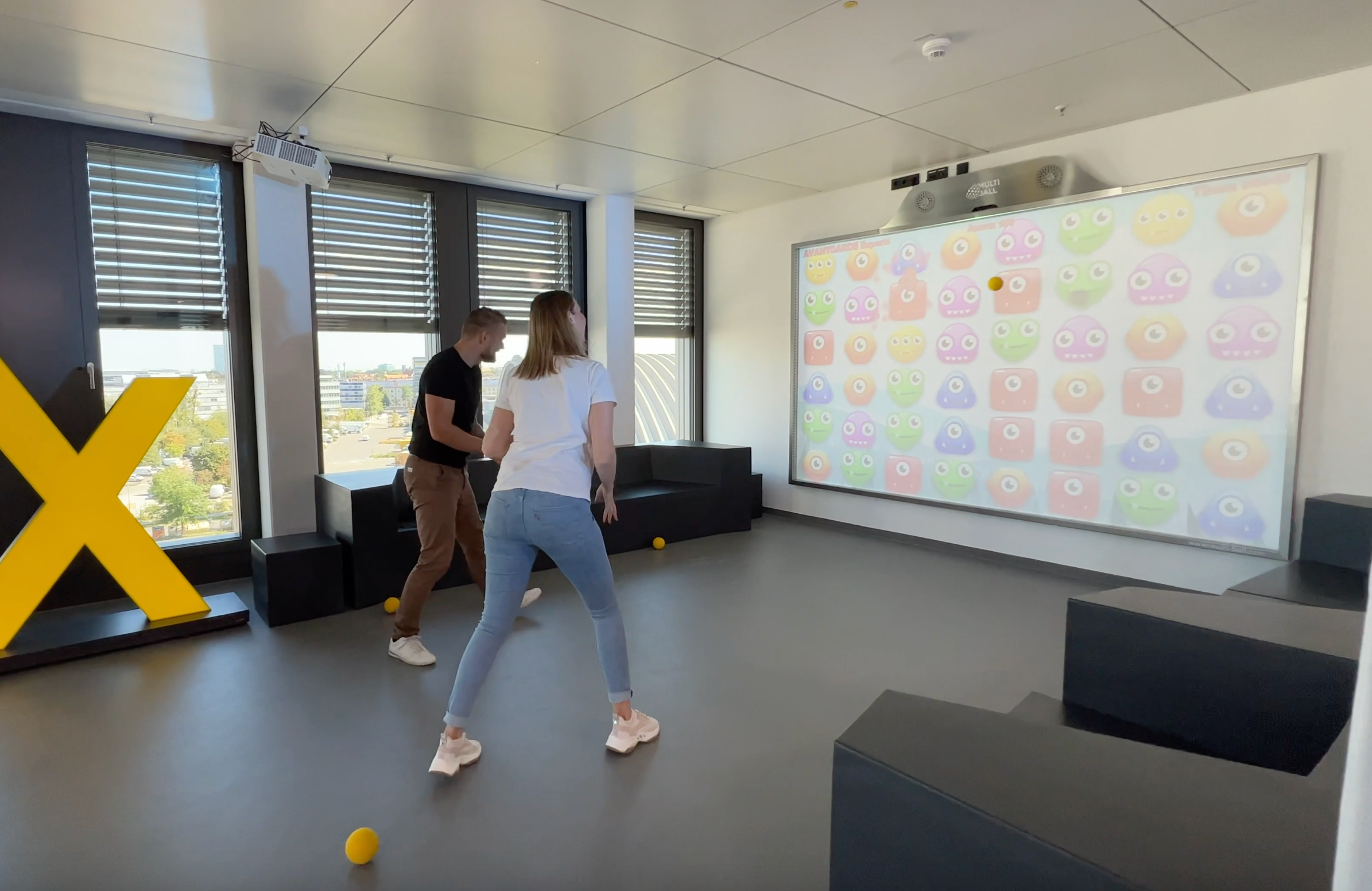 Two people playing the game Monster Match on an interactive MultiBall projector system in an office building