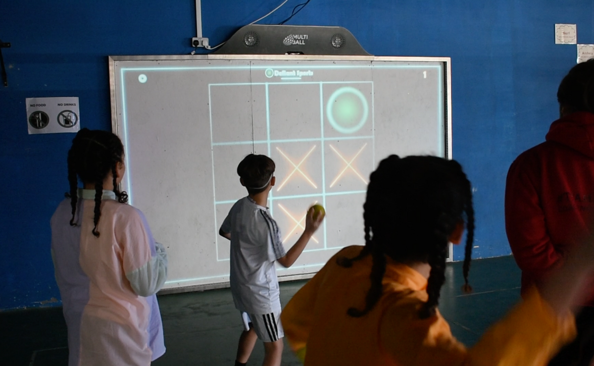 Kids playing Tic Tac Toe by throwing balls at the interactive wall MultiBall at the inclusive sports center Defiant Sports