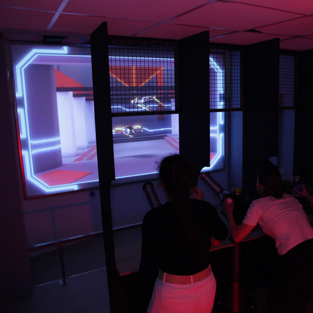 Two people playing a game on the interactive MultiBall wall in a dark arcade room.