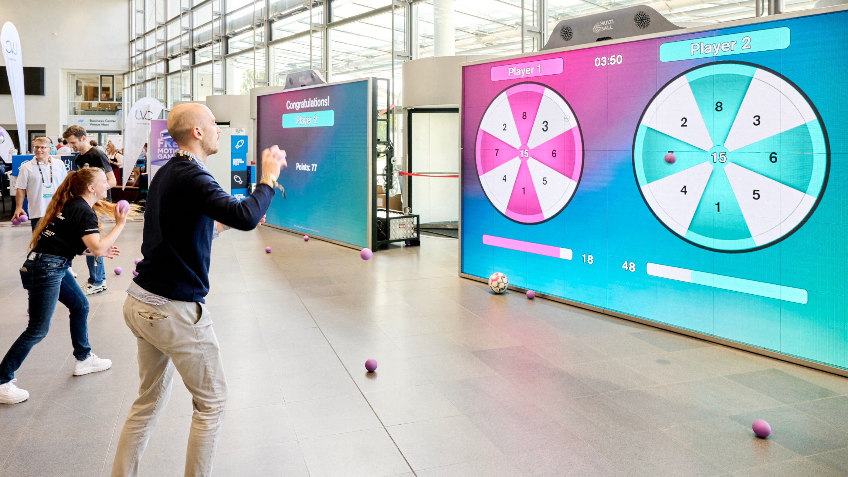Person interacting with a MultiBall LED screen displaying a game interface at an event.