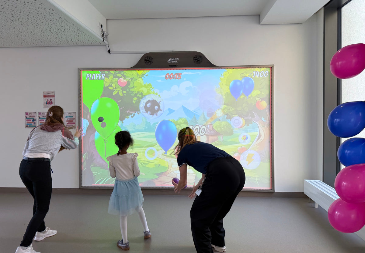 One children and two sport therapists at the Kinderklinik Schwabing München throwing at the Balloons in the Ballon Mania game on MultiBall.