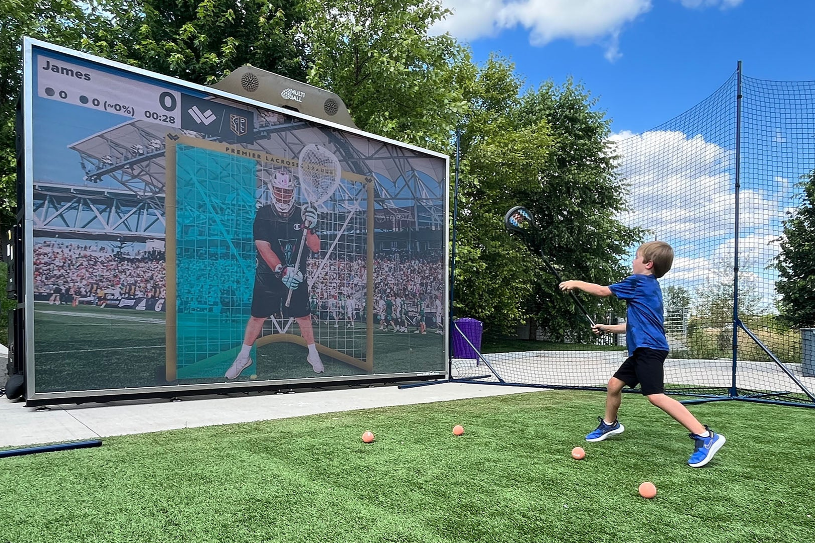 A little boy playing lacrosse on the interactive wall MultiBall