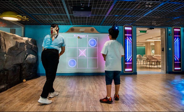 Two people playing the game Tic Tac Toe with softballs on the interactive MultiBall system in an arcade room