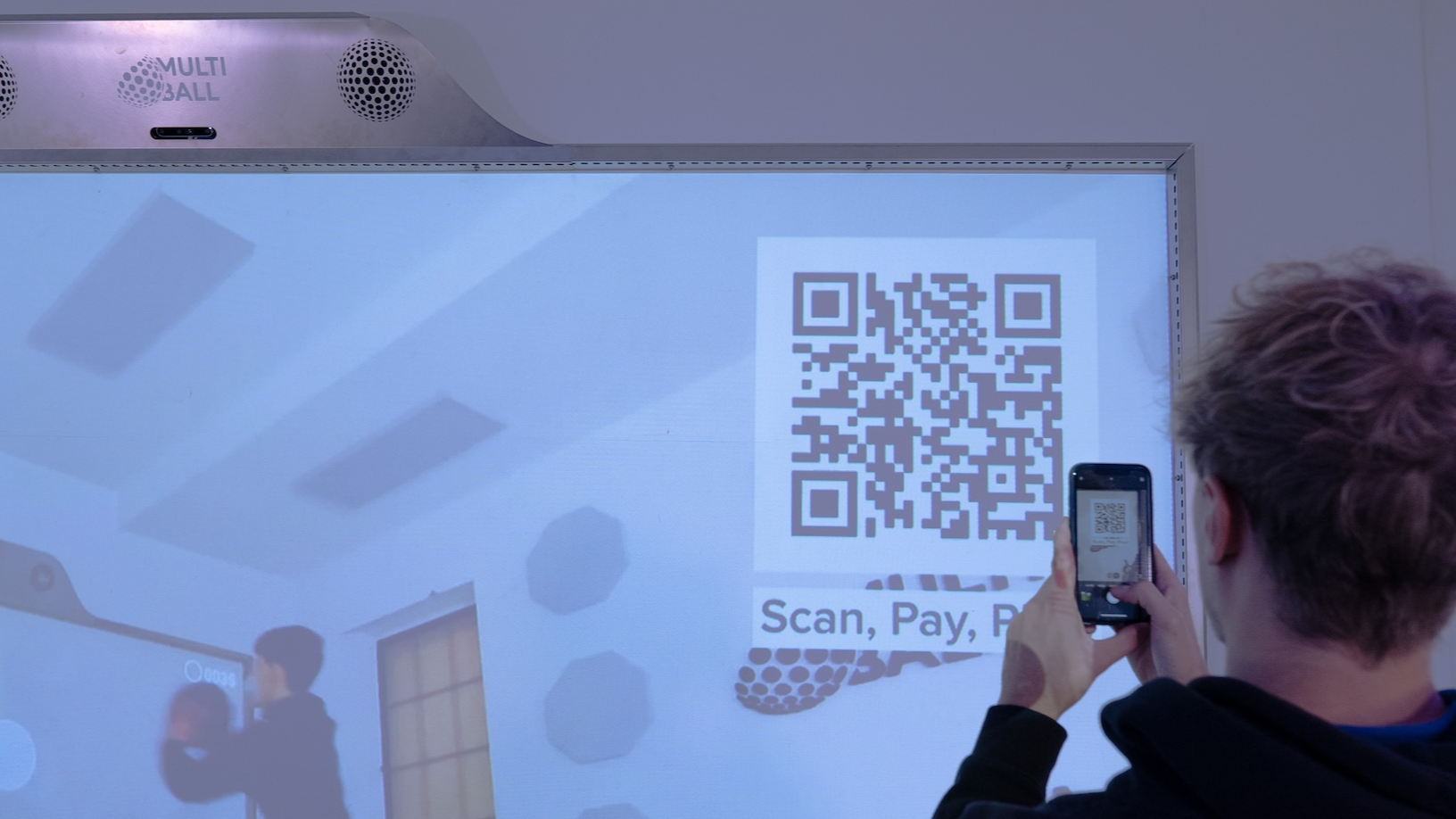 Person scanning a QR-Code which is shown on the interactive wall MultiBall