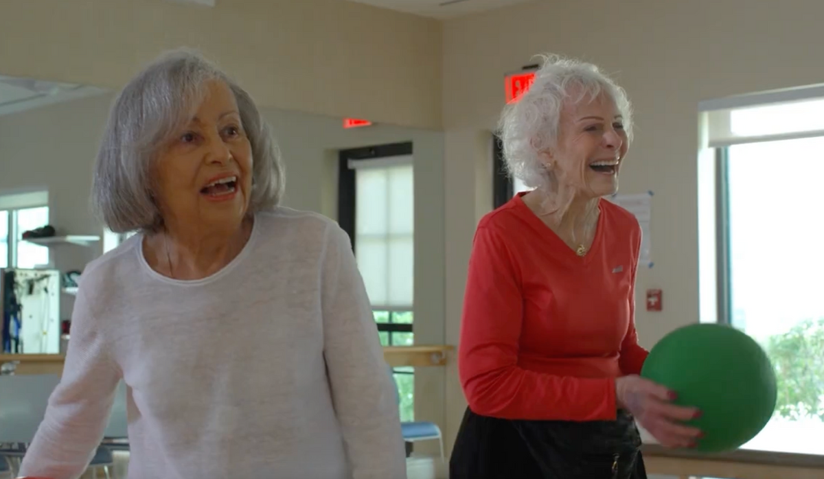 Two elderly women in a room with a green ball playing at a MultiBall system