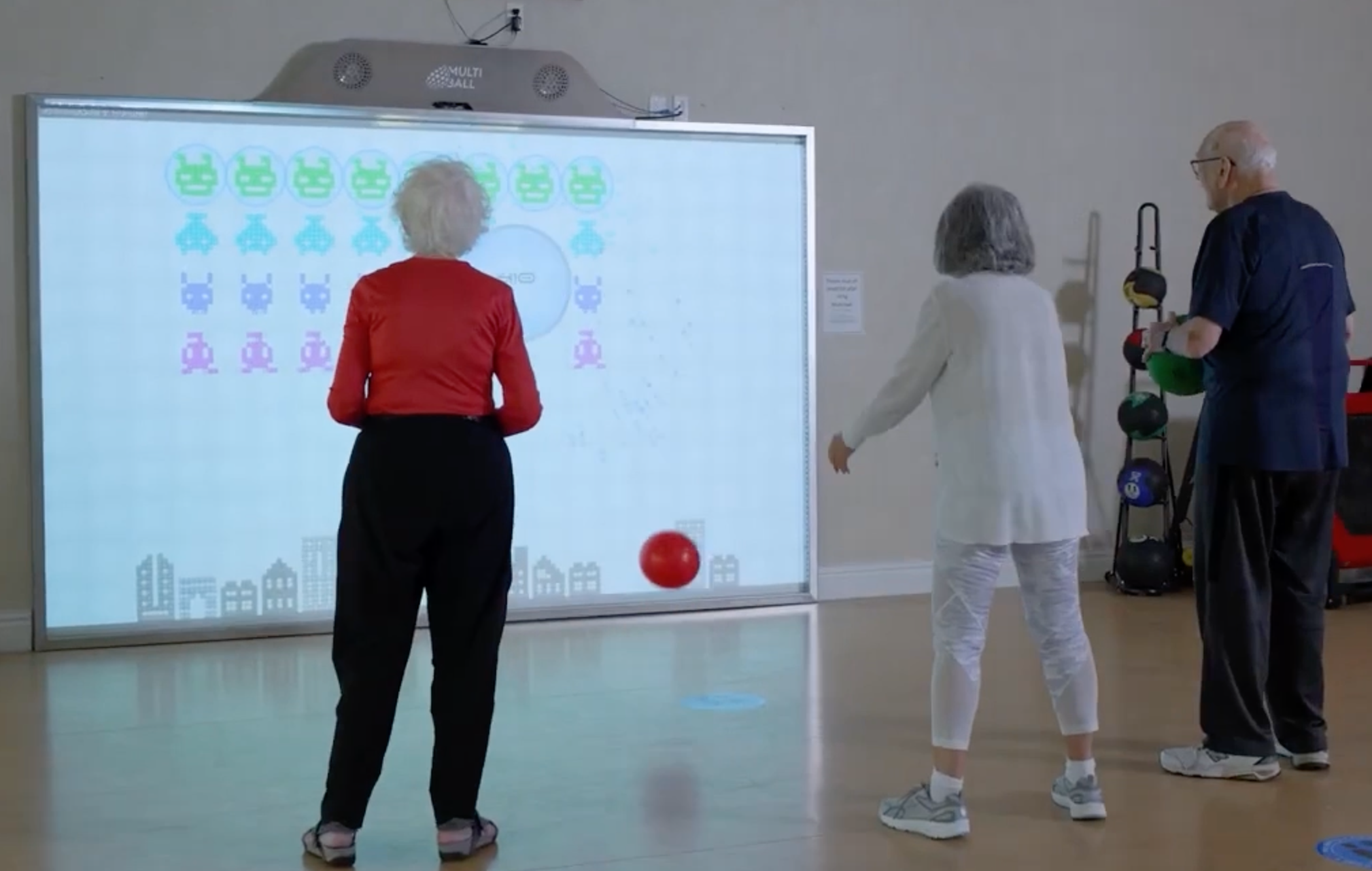 Three Seniors playing Invaders on the MultiBall by throwing soft balls at the interactive wall