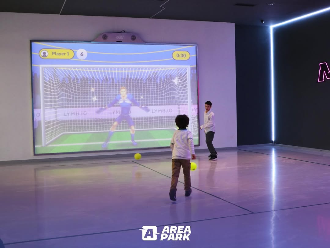 Children playing the soccer video game Goal 3D on a large MultiBall wall in the indoor facility Area Park.