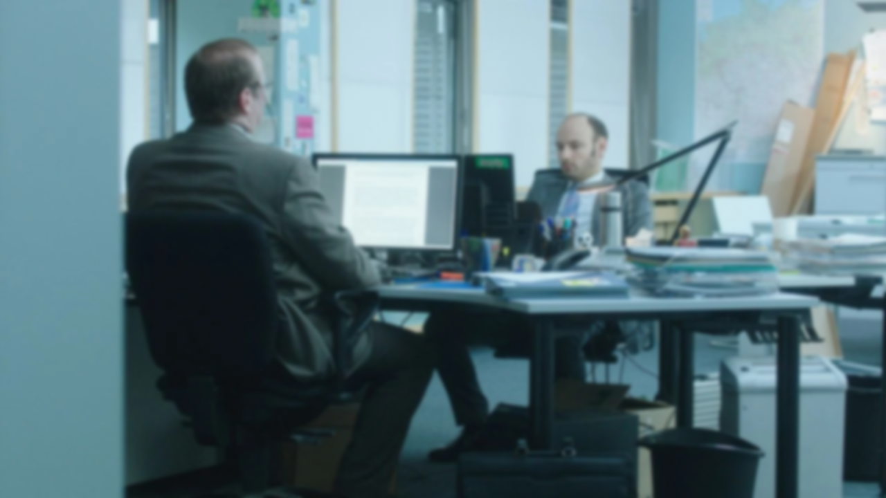 Two people sitting in an office in front of computers