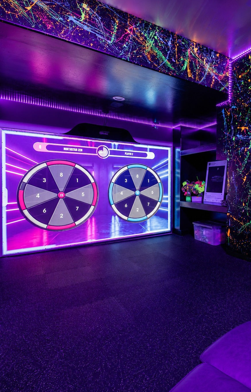 A neon lit PlayRoom with the interactive sports wall MultiBall that has Darts in the 1 vs. 1 mode open at a luxury resort Northstar Zen