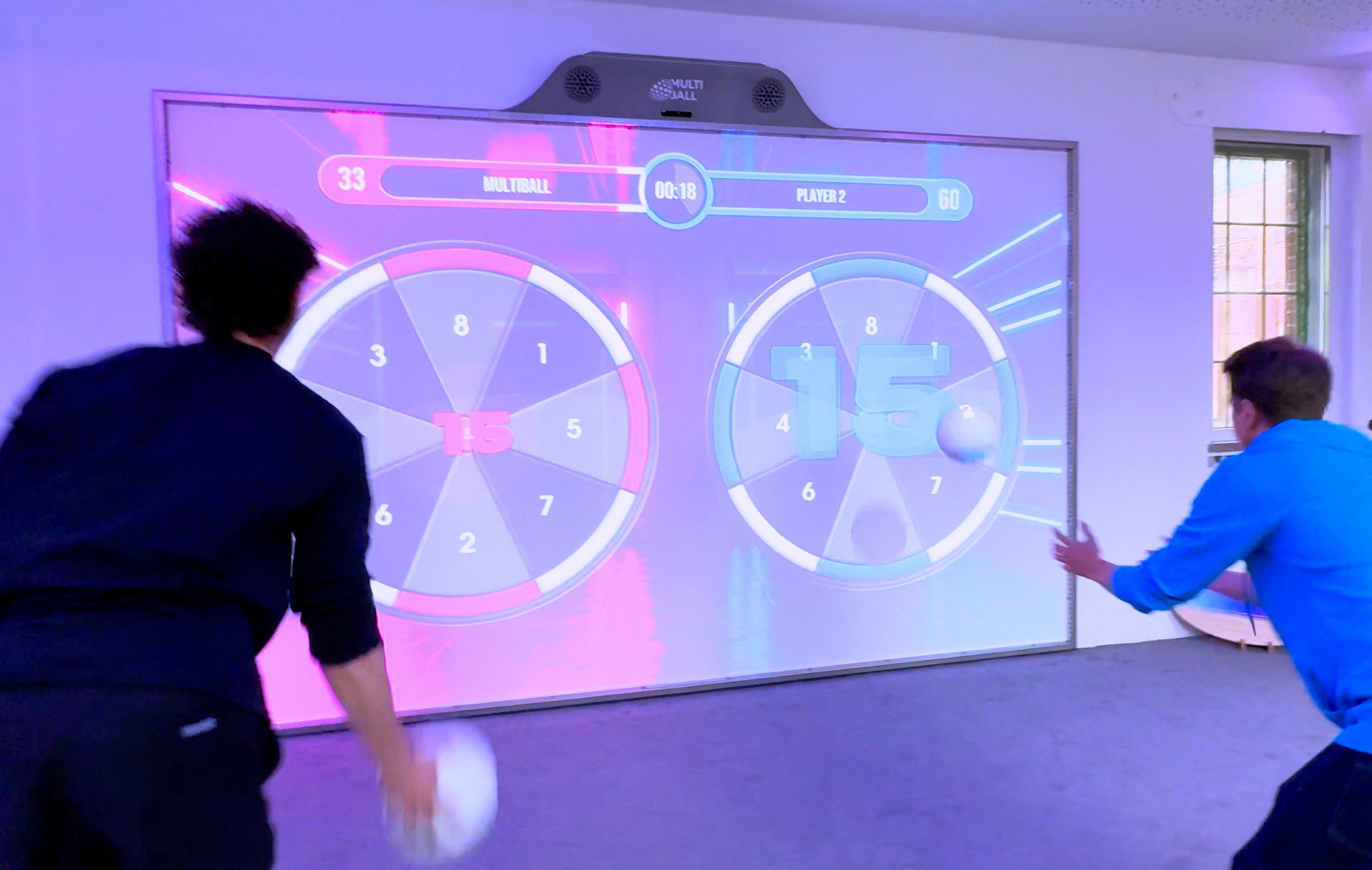 Two players are playing the reworked Darts game on the interactive sports wall MultiBall in Splitscreen Classic Mode