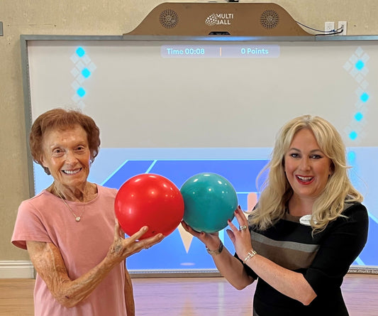 The Owner and a senior in Sinai Residences showing their happiness for their MultiBall by showing the soft balls in front of the interactive wall