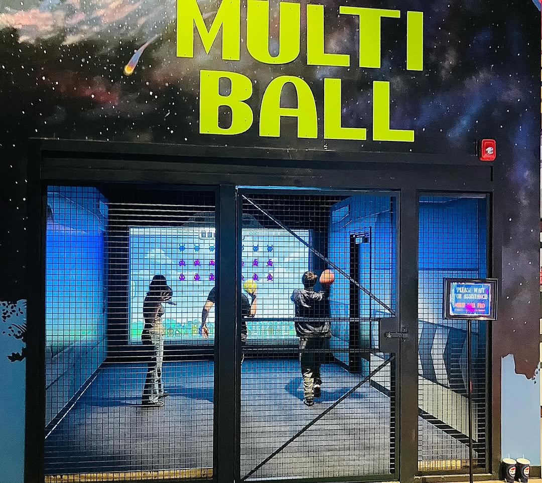 Indoor play area with 'MULTIBALL' sign and people playing the game Alien Hunt.