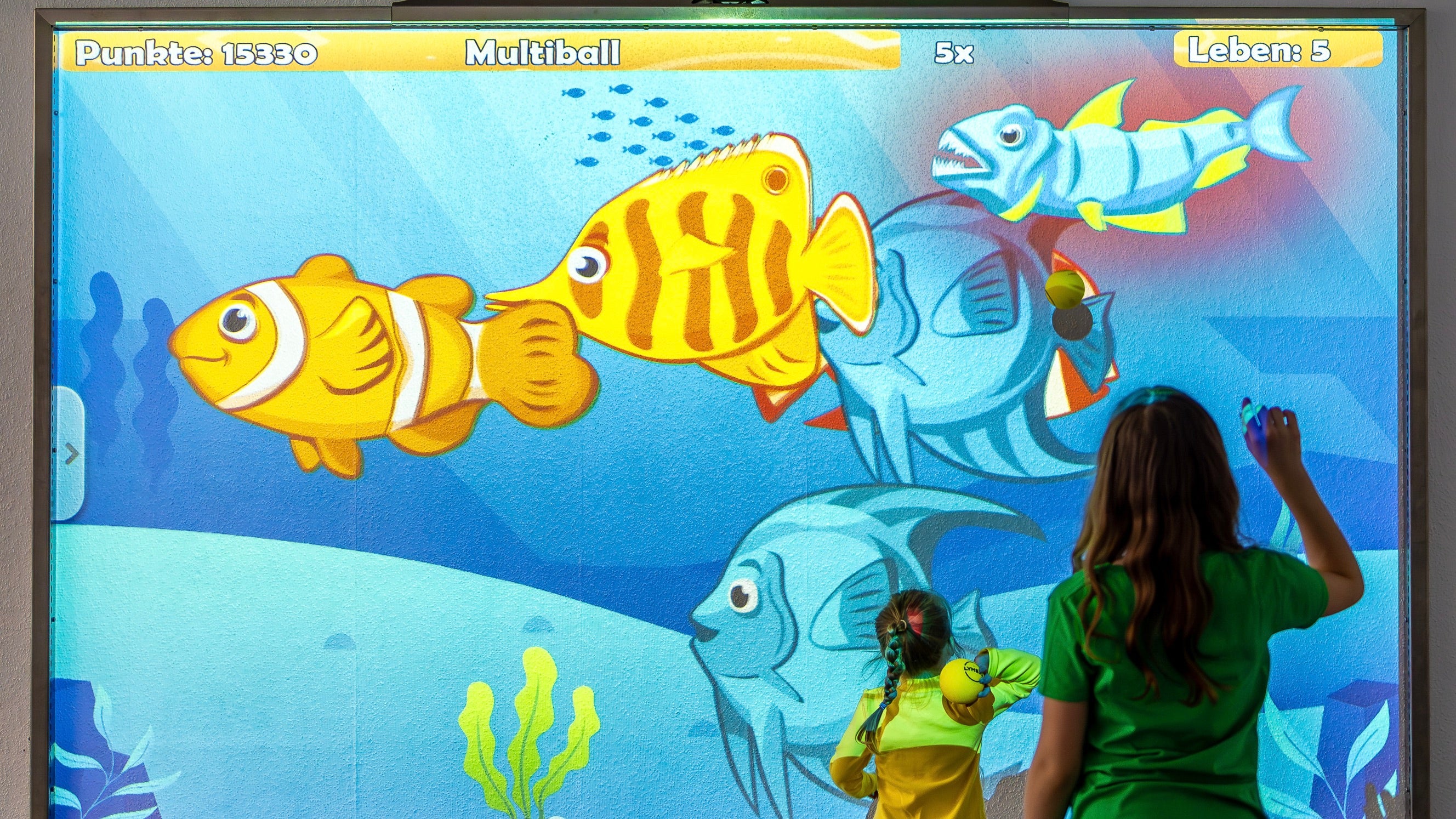 Two kids playing the game Ocean on the interactive wall MultiBall at an indoor playground in Greifswald in Germany