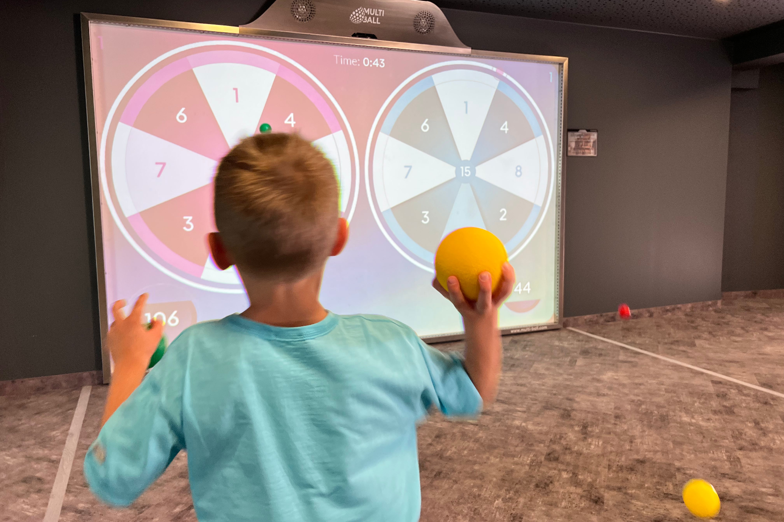 A kid playing the game darts on the interactive wall MultiBall at Hotel Laurentius