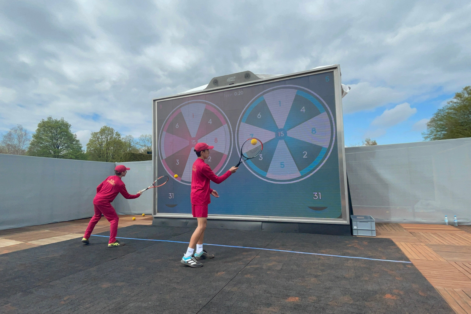 Two people playing tennis outside on the MultiBall wall in the game Darts