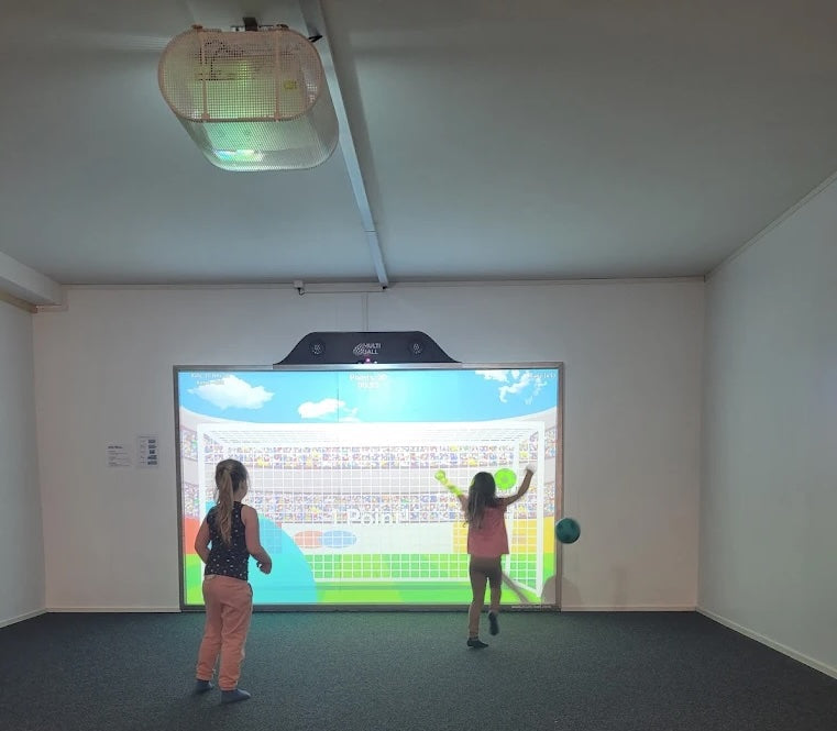 Two children playing a video game on the interactive wall MultiBall in a room at the indoor playground and trampoline park Fägnäscht.